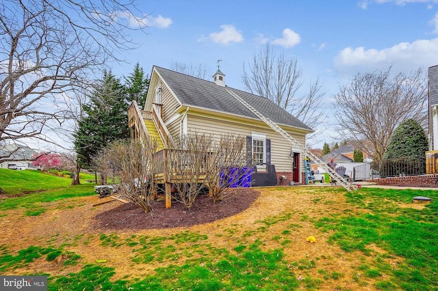 rear view of property with stairs, roof with shingles, a lawn, and brick siding