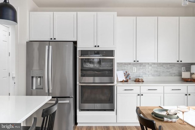kitchen with stainless steel appliances, light countertops, white cabinets, and decorative backsplash