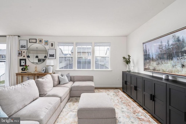living room featuring healthy amount of natural light, light wood-style flooring, and baseboards