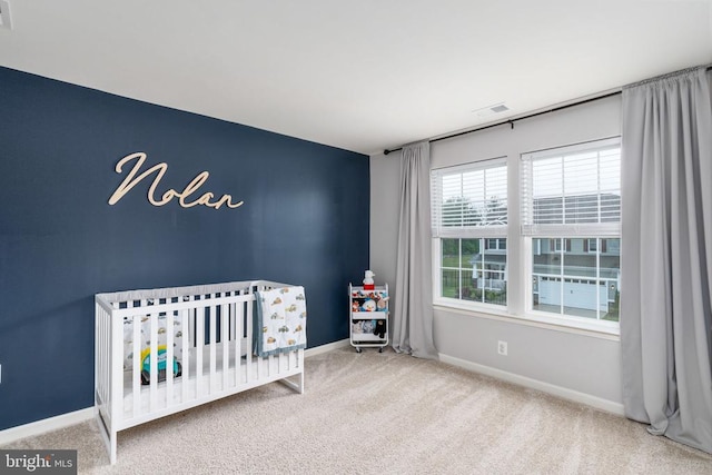 carpeted bedroom with a nursery area and baseboards