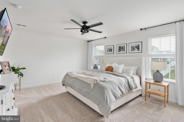bedroom featuring light colored carpet, baseboards, and ceiling fan