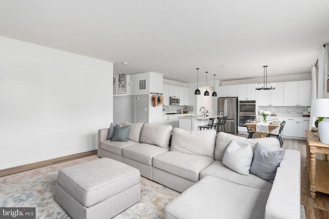 living area with light wood finished floors and a chandelier