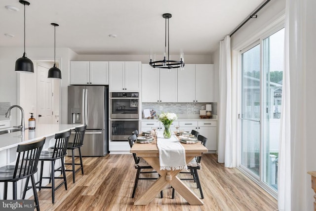 kitchen featuring stainless steel appliances, a sink, decorative backsplash, and light wood-type flooring