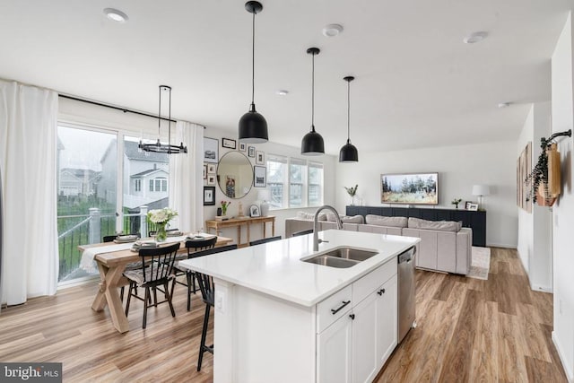 kitchen with a sink, light wood-type flooring, light countertops, and a kitchen island with sink