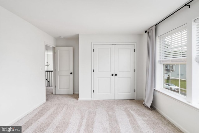 unfurnished bedroom with carpet floors, a closet, and baseboards