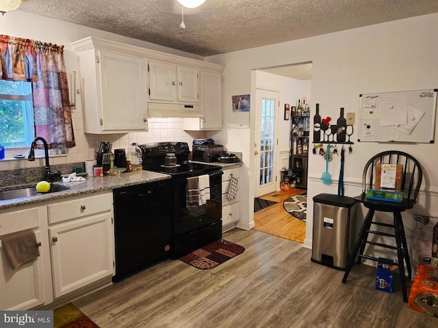 11708 Eisenhower Ln, Fredericksburg, VA 22407 - kitchen with black appliances, wood finished floors, a textured ceiling, white cabinets, and tasteful backsplash