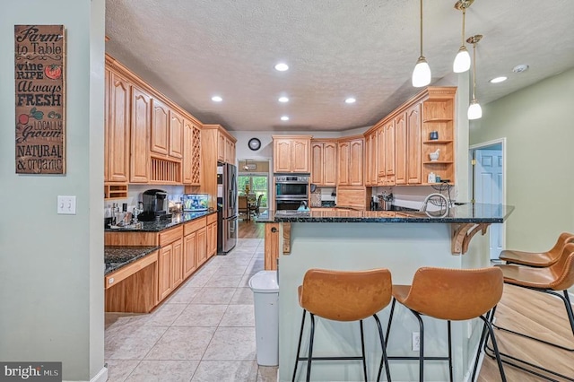 520 Oak Grove Dr, Mineral, VA 23117 - kitchen with stainless steel appliances, a breakfast bar area, a peninsula, dark stone counters, and recessed lighting