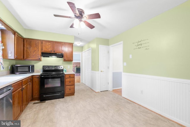 5310 Leavells Crossing Dr, Fredericksburg, VA 22407 - kitchen featuring black appliances, under cabinet range hood, wainscoting, light countertops, and brown cabinetry