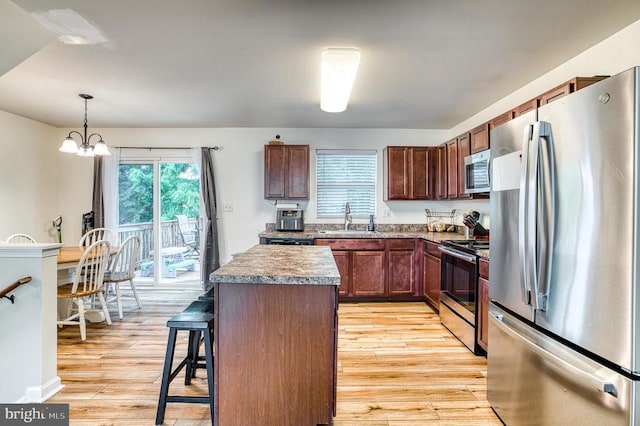 1905 Crepe Myrtle Ln, Culpeper, VA 22701 - kitchen with stainless steel appliances, a center island, a kitchen bar, light wood-type flooring, and decorative light fixtures