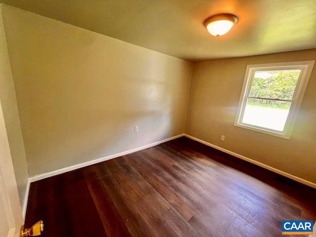 spare room with baseboards and dark wood finished floors