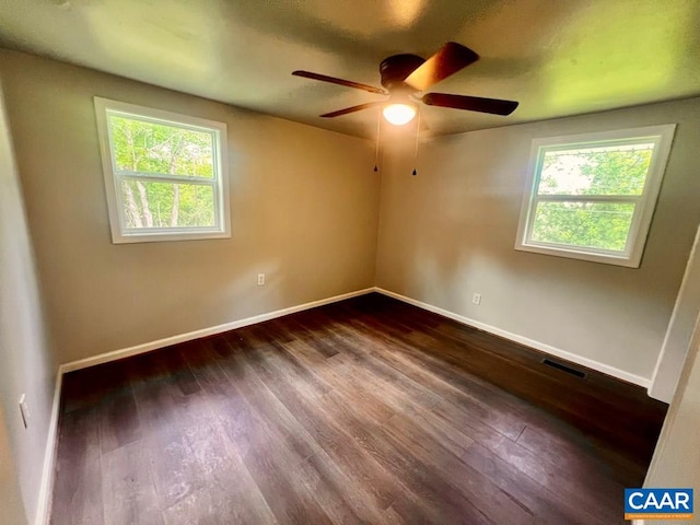 empty room with plenty of natural light, visible vents, dark wood-style flooring, and ceiling fan