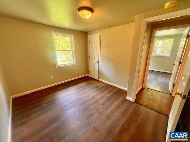 unfurnished bedroom featuring baseboards, dark wood finished floors, and a closet