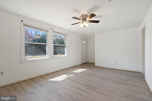 empty room with a textured ceiling, baseboards, wood finished floors, and a ceiling fan