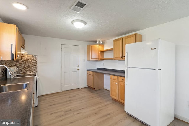 kitchen featuring freestanding refrigerator, light wood-style floors, visible vents, and dark countertops
