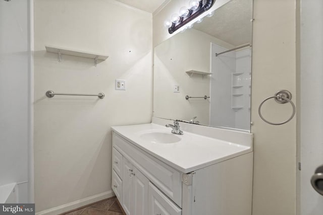 bathroom with baseboards, ornamental molding, tile patterned floors, vanity, and a shower