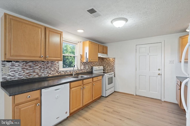 kitchen featuring white appliances, visible vents, a sink, dark countertops, and light wood-type flooring