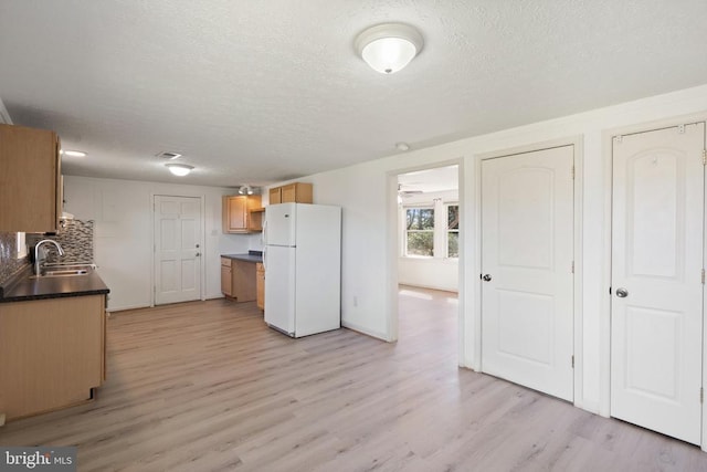 kitchen with freestanding refrigerator, dark countertops, a textured ceiling, and a sink