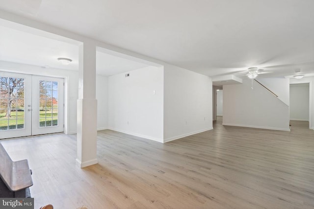unfurnished living room with french doors, light wood-style flooring, baseboards, and ceiling fan