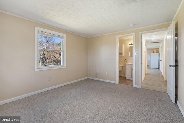 unfurnished bedroom featuring freestanding refrigerator, carpet, a textured ceiling, baseboards, and ornamental molding