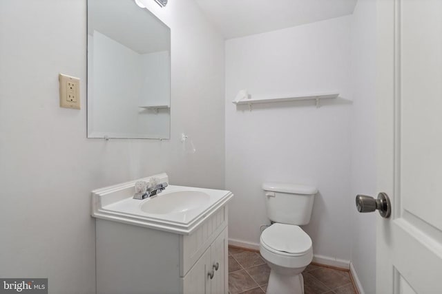 bathroom with toilet, baseboards, tile patterned floors, and vanity