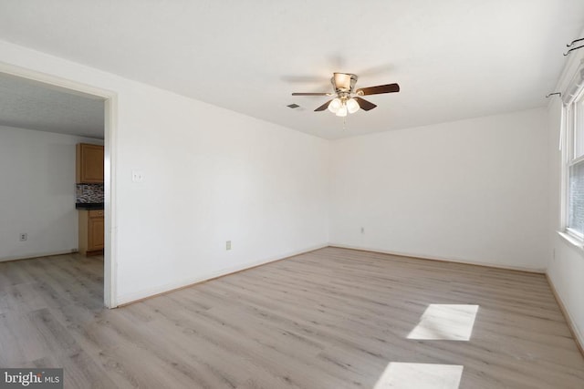 empty room with ceiling fan, light wood-style flooring, baseboards, and visible vents