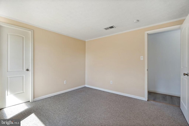 unfurnished room featuring crown molding, carpet, baseboards, and visible vents