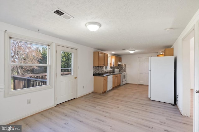 kitchen with a textured ceiling, white appliances, a sink, backsplash, and light wood-style floors