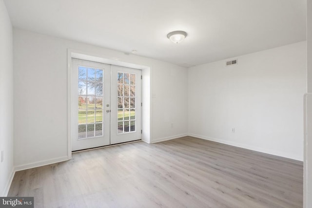 empty room featuring baseboards, french doors, visible vents, and wood finished floors