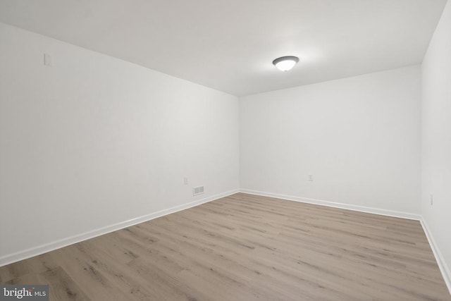spare room with baseboards and wood finished floors