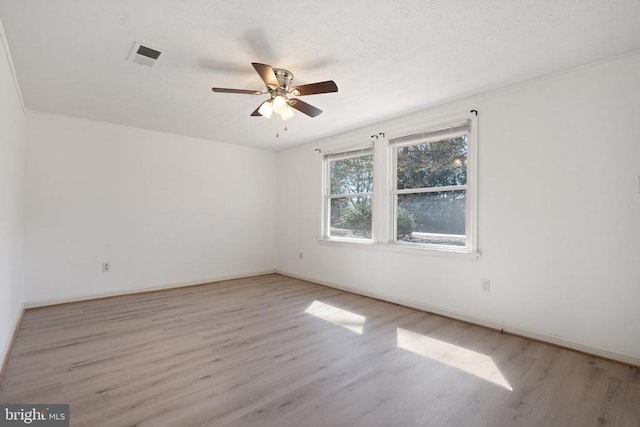 unfurnished room with light wood finished floors, baseboards, a ceiling fan, and visible vents
