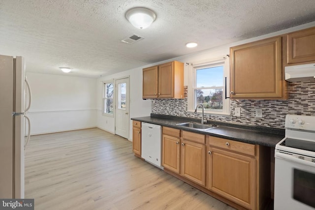kitchen featuring a sink, a textured ceiling, white appliances, and tasteful backsplash