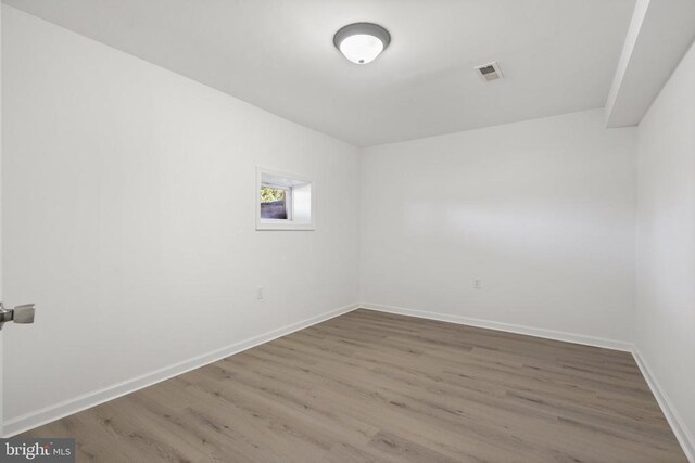 spare room featuring baseboards, visible vents, and wood finished floors