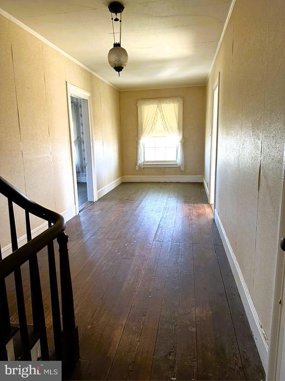 empty room with ornamental molding, hardwood / wood-style floors, and stairs