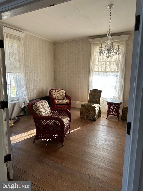 living area featuring radiator, wallpapered walls, a chandelier, and wood finished floors