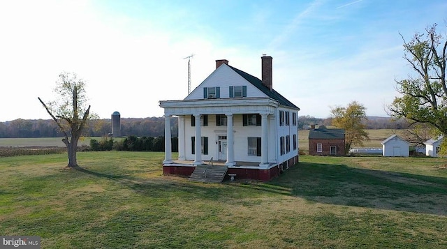 rear view of house featuring a yard, a chimney, and covered porch