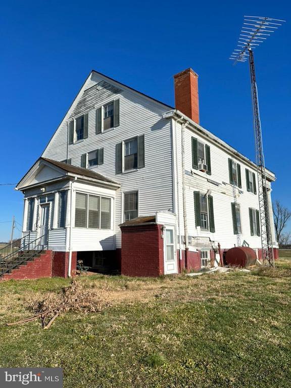 back of property with a chimney and a lawn