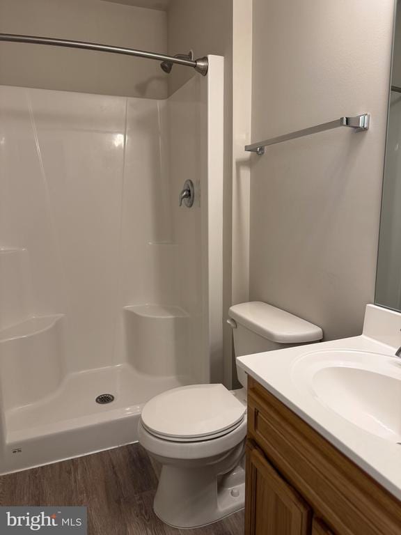 full bath featuring wood finished floors, vanity, a shower, and toilet