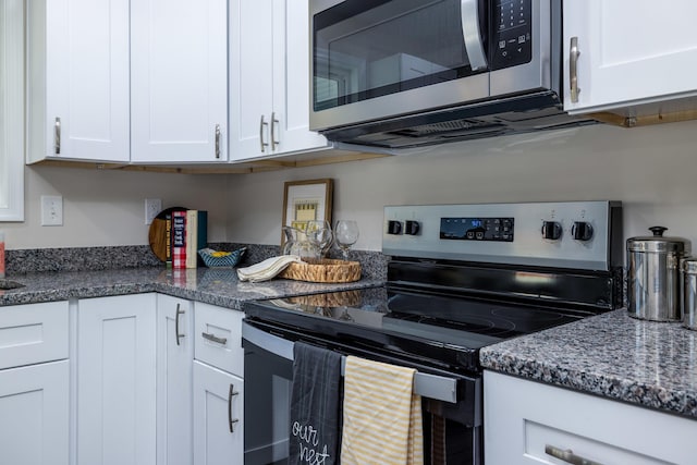 kitchen featuring white cabinets, appliances with stainless steel finishes, and dark stone countertops
