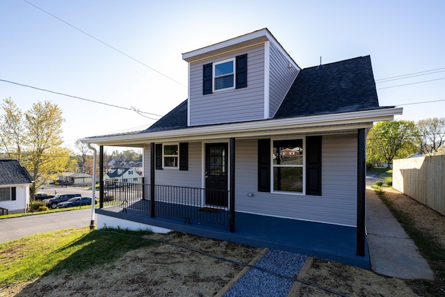 bungalow featuring a porch, roof with shingles, and fence