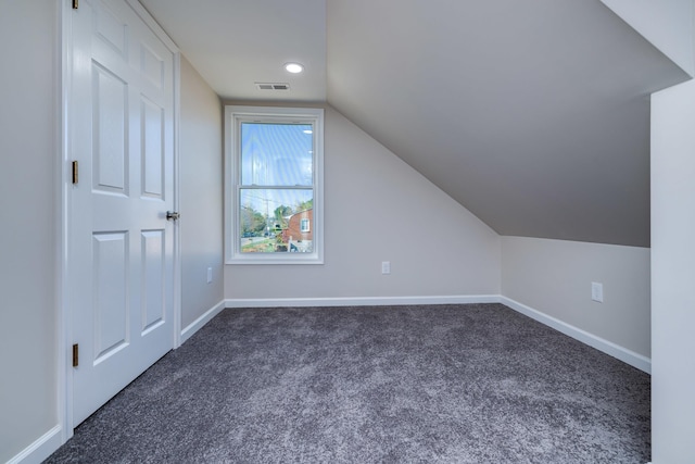additional living space with visible vents, recessed lighting, vaulted ceiling, baseboards, and dark carpet