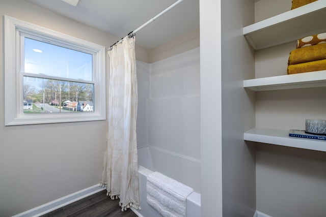 bathroom with baseboards, shower / bath combo with shower curtain, and wood finished floors