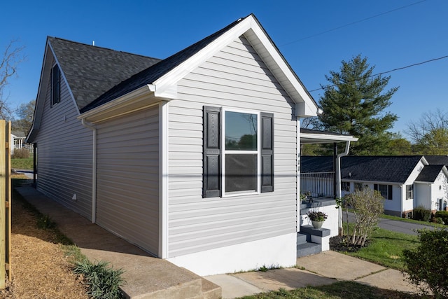 view of side of property with a porch and roof with shingles