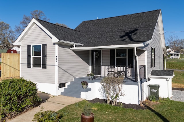 view of front of house with a front lawn, a porch, and roof with shingles