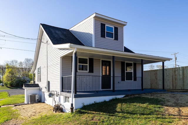 bungalow-style house featuring central air condition unit, a front yard, a shingled roof, and covered porch