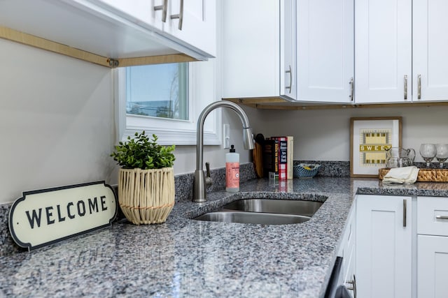kitchen featuring a sink, light stone countertops, and white cabinets
