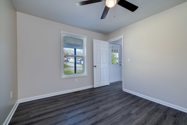 empty room with baseboards, ceiling fan, and dark wood-style floors