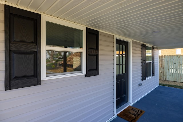 doorway to property with a porch and fence
