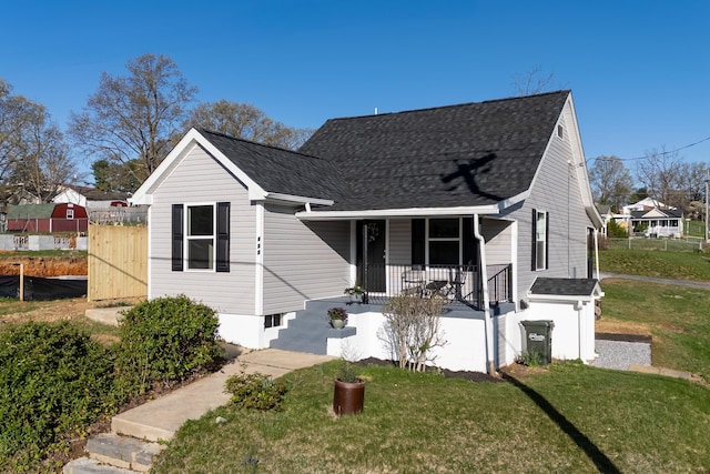 bungalow-style home featuring a porch, roof with shingles, a front lawn, and fence