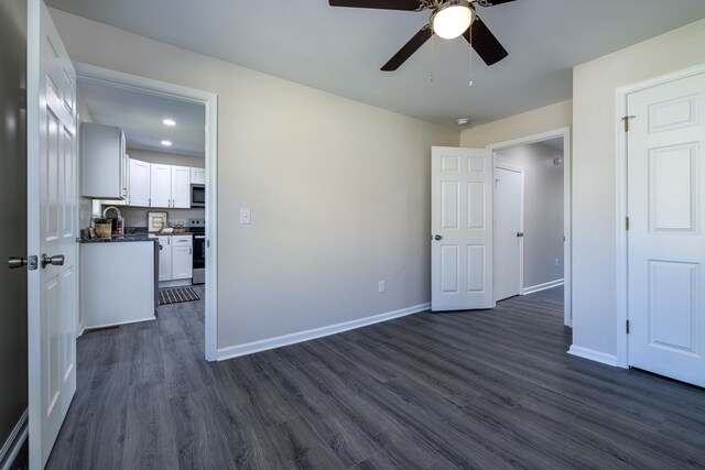 unfurnished bedroom with recessed lighting, dark wood finished floors, baseboards, and a sink