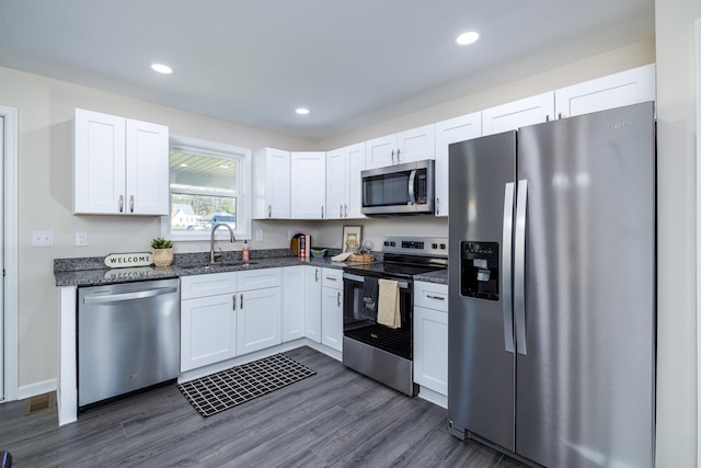 kitchen featuring appliances with stainless steel finishes, dark wood-style flooring, a sink, and white cabinetry